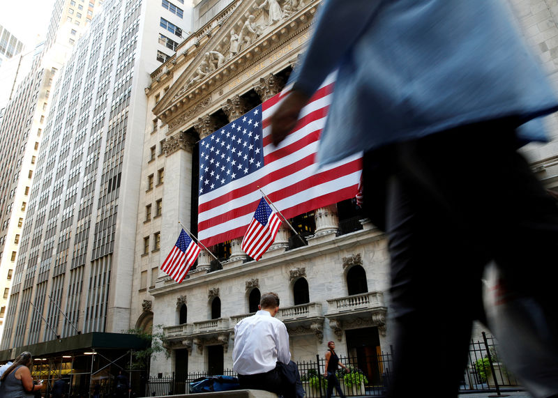 © Reuters. FILE PHOTO: People sit outside the NYSE during the morning commute