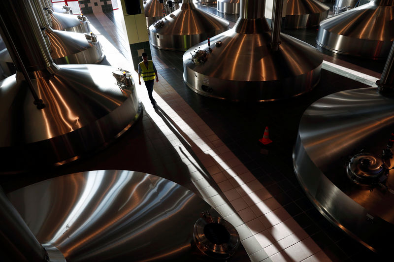© Reuters. A worker walks near beer fermentation vats at Anheuser-Busch InBev brewery in Leuven