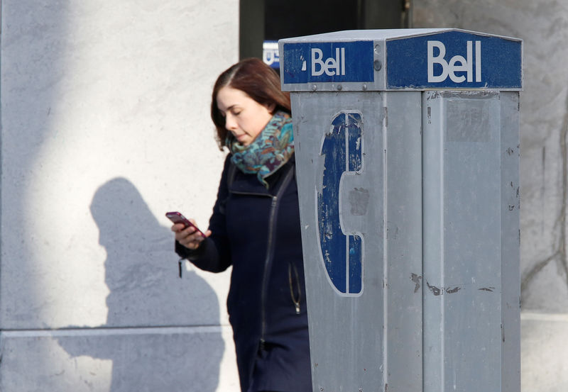 © Reuters. FILE PHOTO: A woman uses a mobile device while walking past a Bell payphone in Ottawa