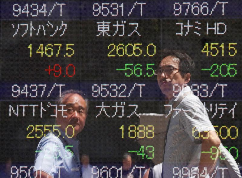 © Reuters. Passersby are reflected on a stock quotation board outside a brokerage in Tokyo