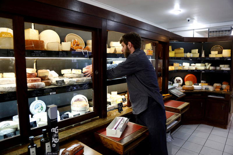 © Reuters. FILE PHOTO: A cheesemonger removes cheese at Beaufils affineur in Paris