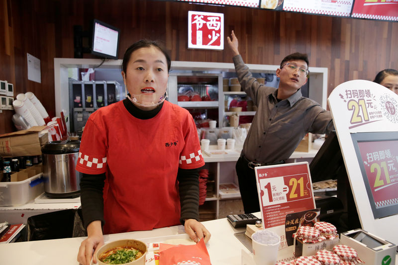 © Reuters. Employees work at a pork bun chain restaurant Xishaoye in Beijing