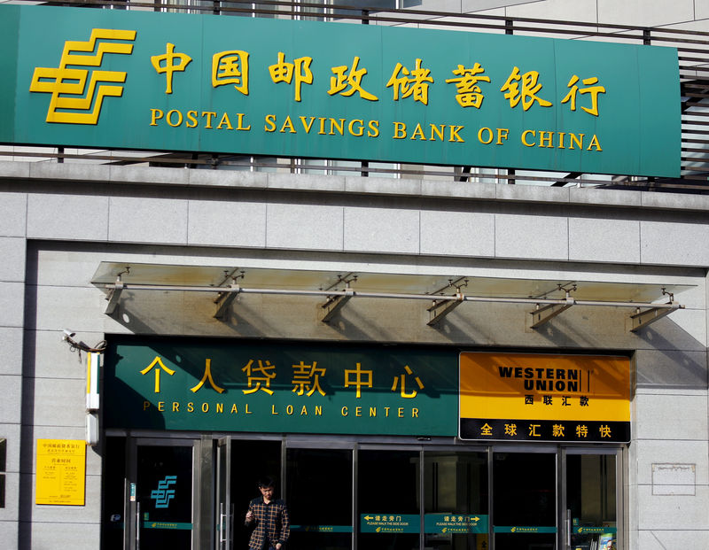 © Reuters. FILE PHOTO: Man walks out of a Postal Savings Bank of China branch in Beijing