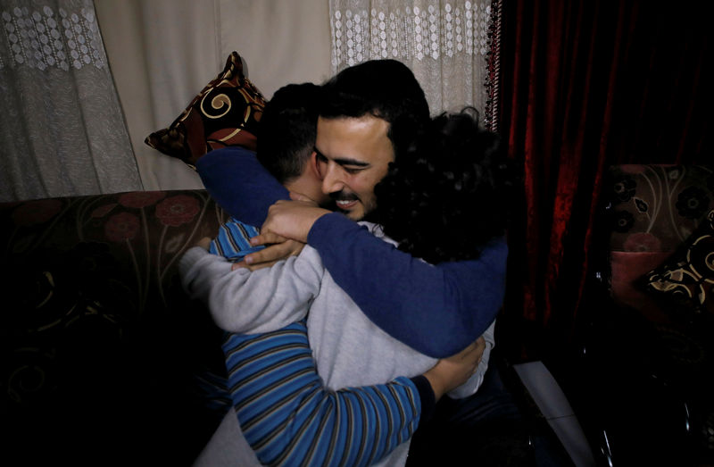 © Reuters. Palestinian journalist, Yaghi, hugs his younger brothers in Banha