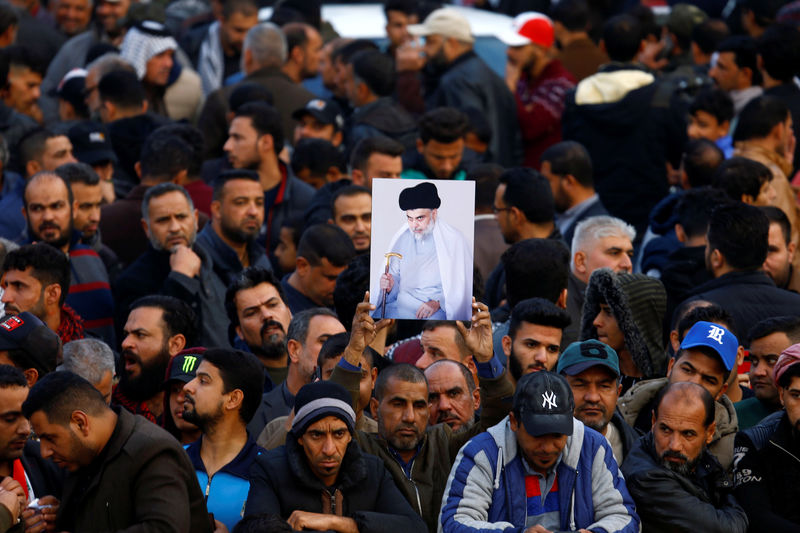 © Reuters. Supporters of Iraqi Shi'ite cleric Moqtada al-Sadr carry his picture near his home, after it was attacked, in the holy city of Najaf