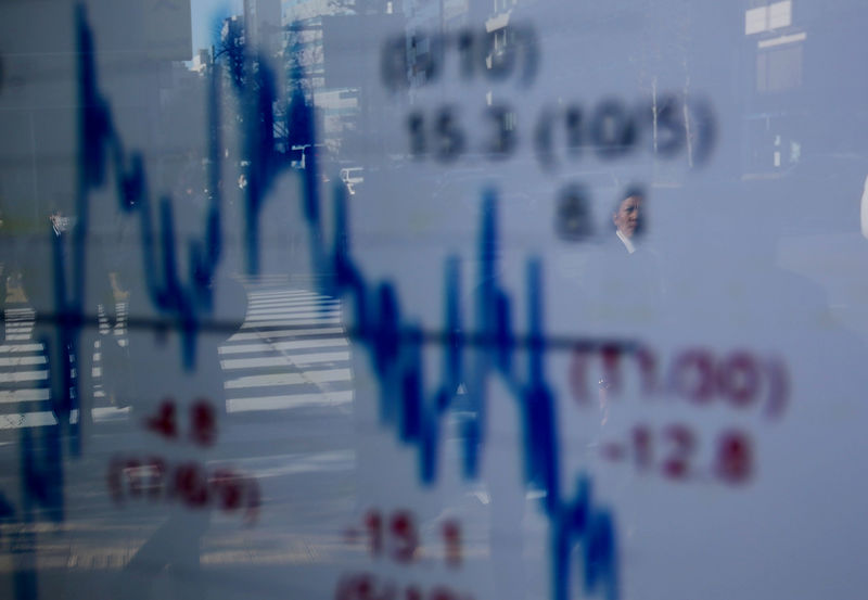 © Reuters. A man is reflected on an electronic board showing a graph analyzing recent change of Nikkei stock index outside a brokerage in Tokyo