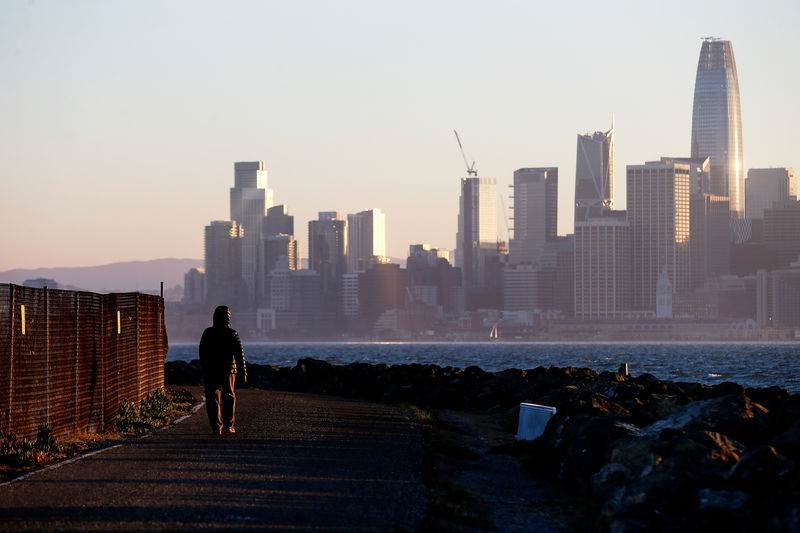 © Reuters. FILE PHOTO: The San Francisco skyline is seen behind a woman as she walks past a condemned area on Treasure Island, near San Francisco
