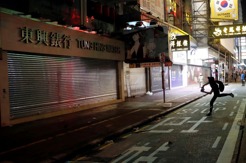 © Reuters. FILE PHOTO: Anti-government protester throws stone at watch retailer in Hong Kong