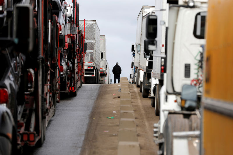 © Reuters. FILE PHOTO: A man stands between trucks waiting in a long queue at border customs control to cross into the U.S, caused by the redeployment of border officers to deal with a surge in migrants, at the Otay border crossing in Tijuana