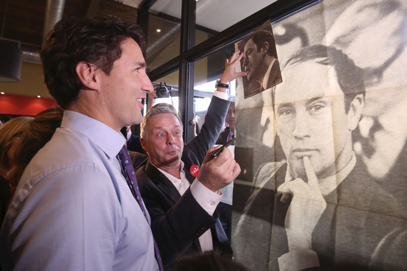 © Reuters. FILE PHOTO: Liberal leader Trudeau looks at a poster of his late father during a campaign stop in Sainte-Therese