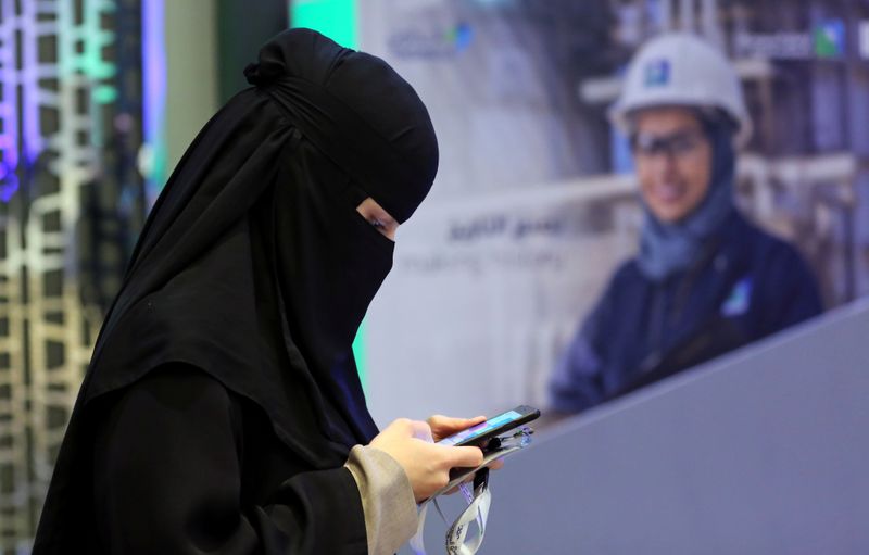 © Reuters. Participant uses her smartphone during the official ceremony marking the debut of Saudi Aramco's IPO on the Riyadh's stock market, in Riyadh