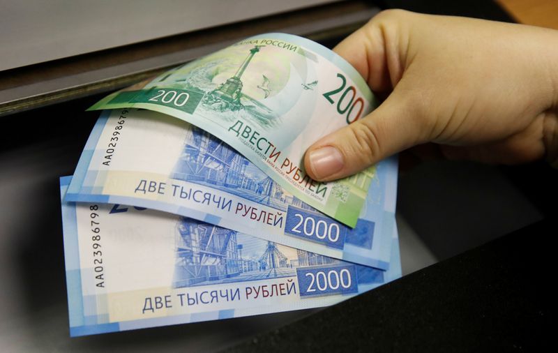 © Reuters. FOTO DE ARCHIVO: Una mujer tiene nuevos billetes de 200 y 2,000 rublos en un banco en Moscú