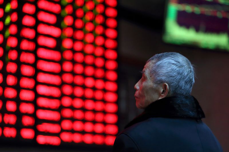 © Reuters. FILE PHOTO:  A man looks on in front of an electronic board showing stock information at a brokerage house in Nanjing