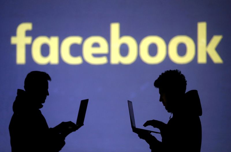© Reuters. FILE PHOTO: Silhouettes of laptop users are seen next to a screen projection of a Facebook logo