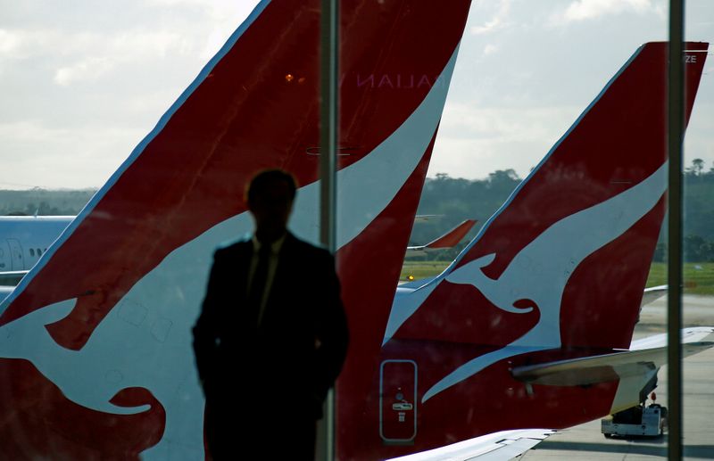 © Reuters. FILE PHOTO: A passenger stands in front of a window where Qantas planes are parked at Melbourne Airport, Australia