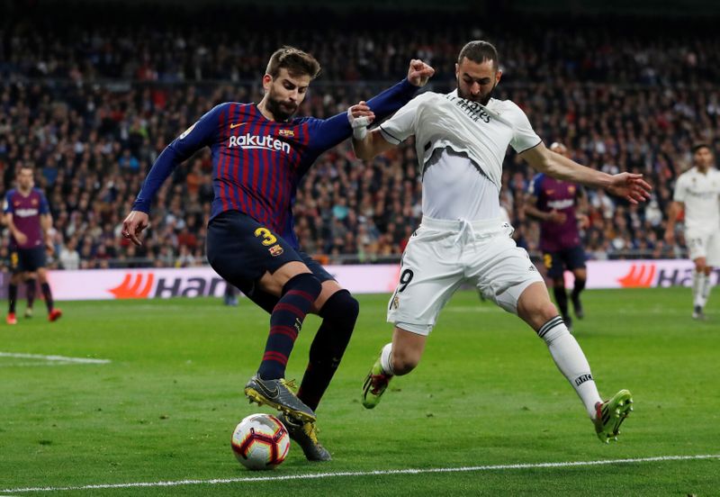 © Reuters. FOTO DE ARCHIVO: Karim Benzema del Real Madrid y Gerard Pique del FC Barcelona, durante un partido de La Liga Santander en el estadio Santiago Bernabeu, Madrid