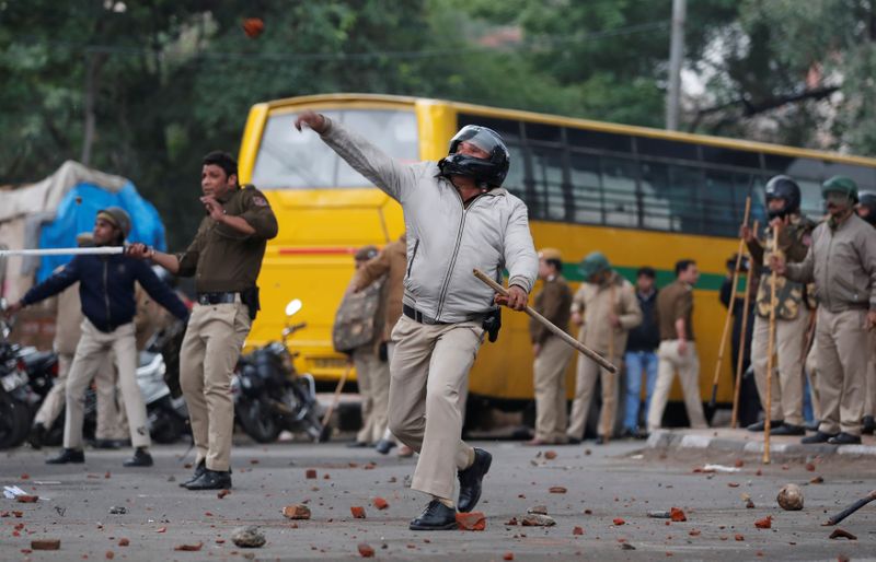 © Reuters. Policial arremessa pedra na direção de manifestantes durante protesto em Nova Délhi