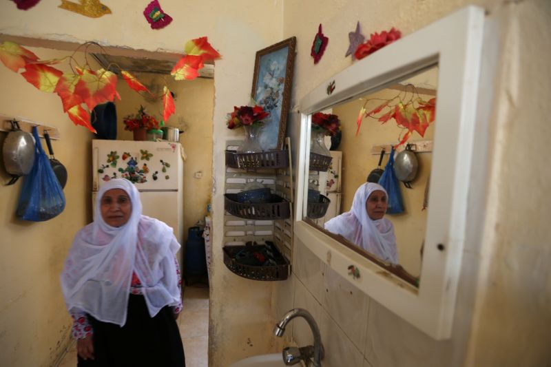 © Reuters. Palestinian refugee Zakeya Moussa is reflected in a mirror as she walks inside her home in Al-Shati refugee camp in Gaza City