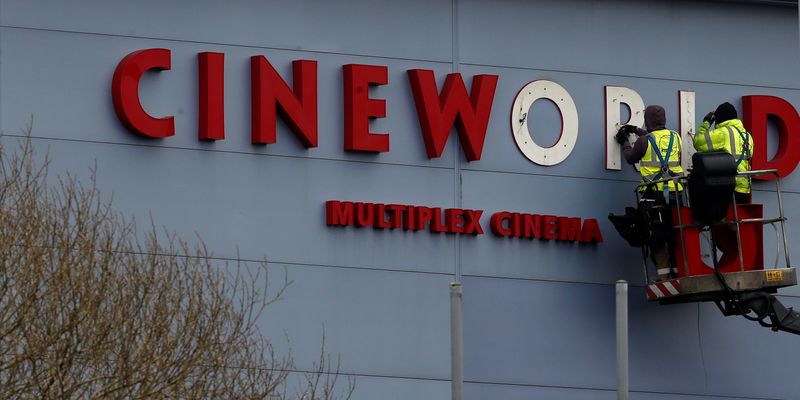 © Reuters. FILE PHOTO Workers repair a sign at a Cineworld cinema in Bradford northern England.