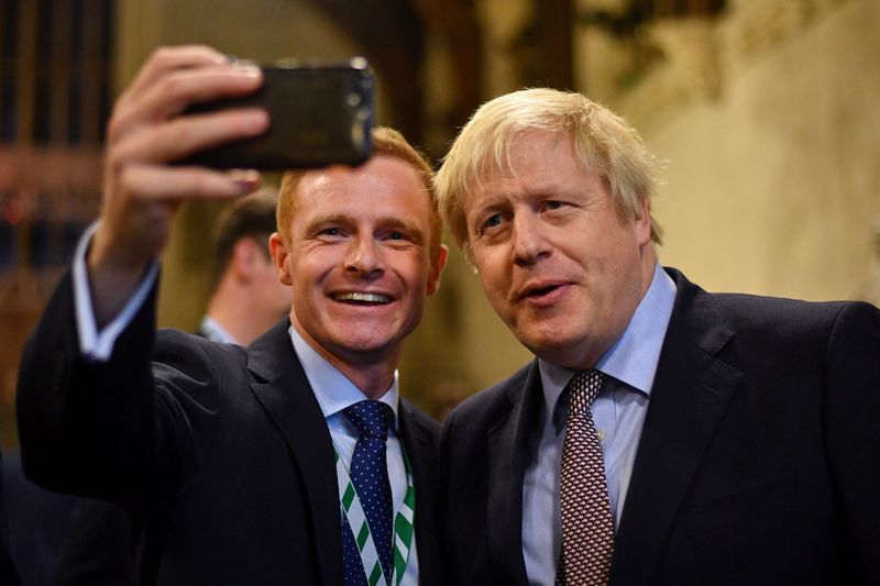 © Reuters. British Prime Minister Boris Johnson poses for a selfie as he greets newly-elected Conservative MPs at the Houses of Parliament, London