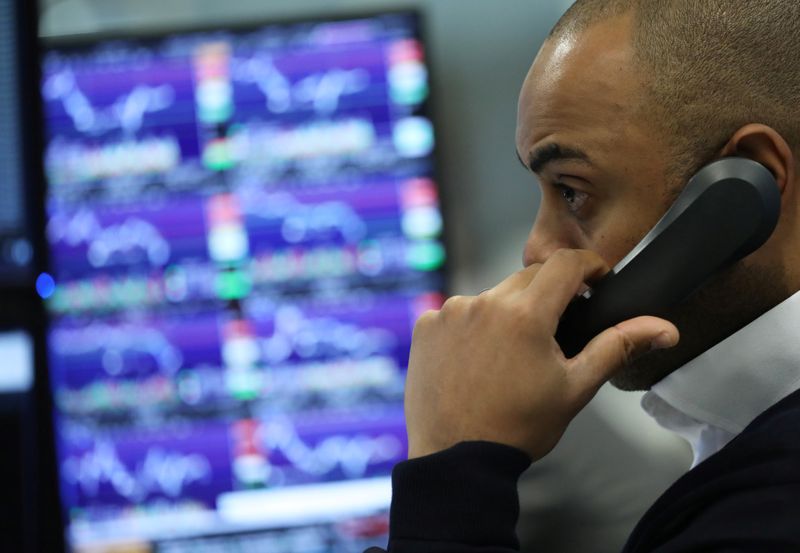 © Reuters. A trader works as screens show market data at CMC markets in London