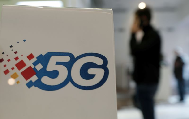 © Reuters. A man uses his phone next to a 5G sign in a telecom shop in Monaco