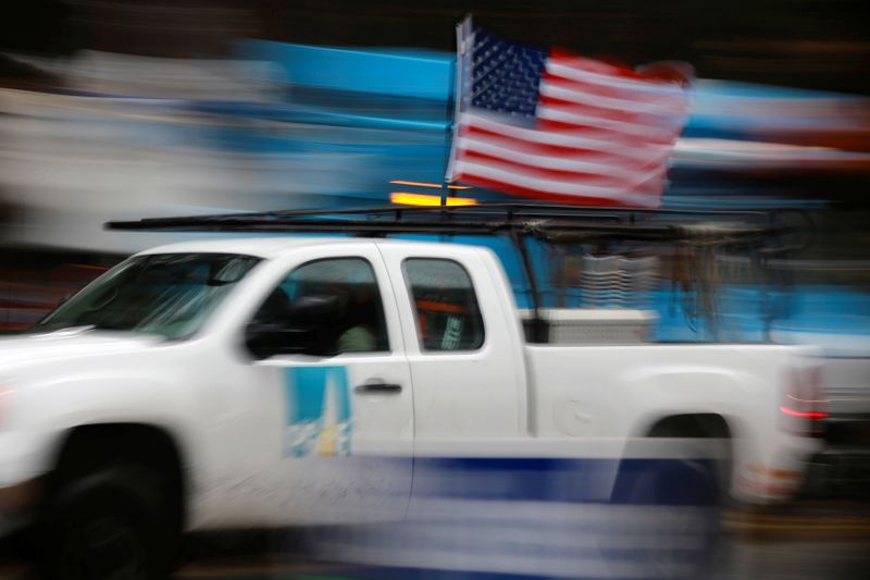 © Reuters. A PG&E truck carrying an American Flag drives past PG&E repair trucks in Paradise