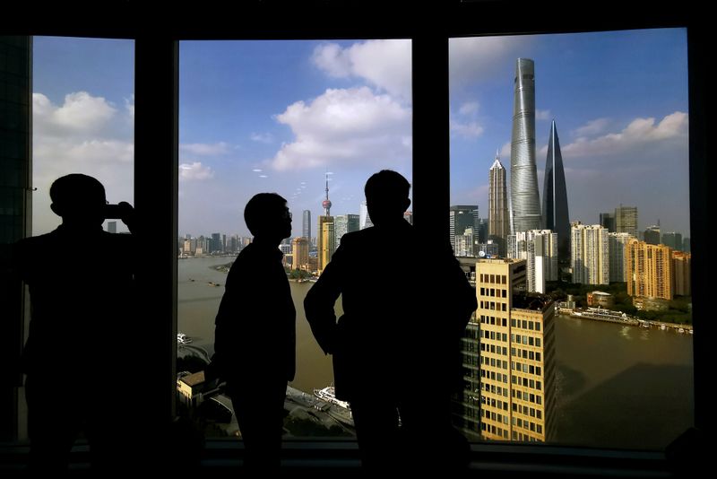 © Reuters. People stand near a window overlooking the financial district in Shanghai