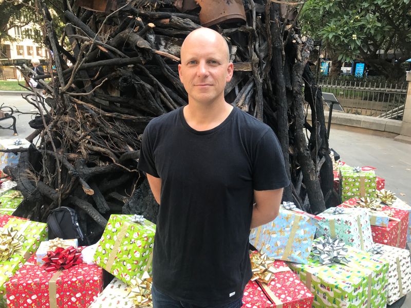 © Reuters. Installation artist, James Dive, stands in front of "Burnt Christmas tree" he built from charred logs and other bushfire remnants as a result of Australia's recent Bushfire crisis, in Sydney