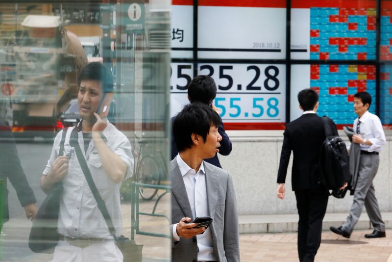 © Reuters. People walk past an electronic board showing Japan's Nikkei average outside a brokerage in Tokyo