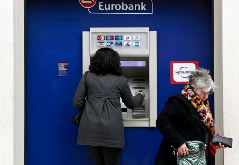 © Reuters. Delle persone davanti ad un bancomat presso una filiale di Eurobank ad Atene, Grecia.