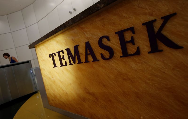 © Reuters. Woman passes a logo of state investor Temasek Holdings at their office in Singapore