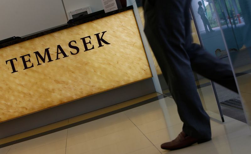 © Reuters. Man passes a logo of state investor Temasek Holdings at their office in Singapore