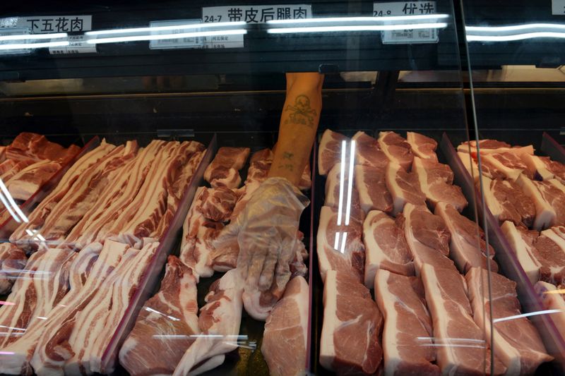© Reuters. Staff member sorts pork slices for sale at a Walmart in Beijing