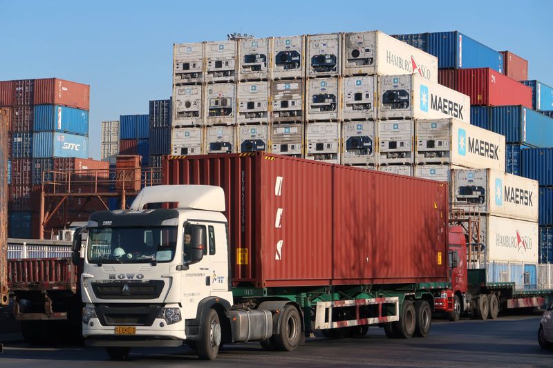 © Reuters. Worker drives a truck carrying a container at a logistics center near Tianjin port