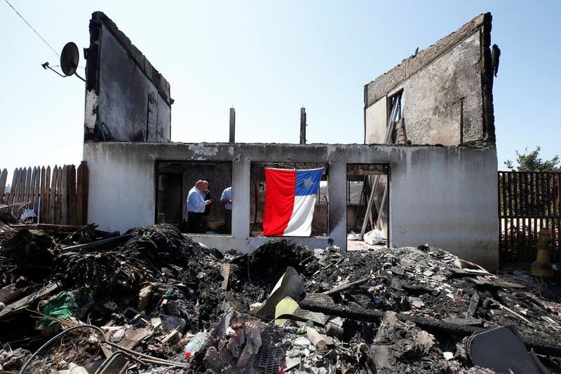 © Reuters. Chilean flag hangs off the remains of a house after it was destroyed by fire in Valparaiso