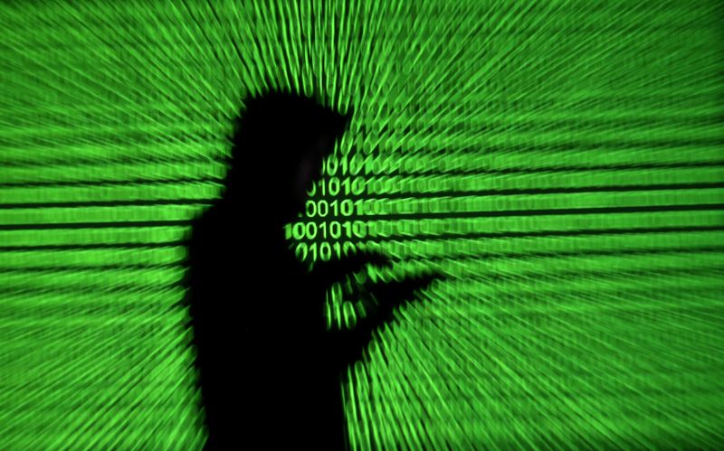 © Reuters. Silhouette of mobile device user is seen next to a screen projection of binary code are seen in this picture illustration