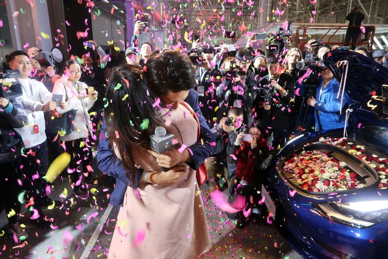 © Reuters. Tesla employee proposes to his girlfriend with a China-made Tesla Model 3 vehicle filled with flowers at a delivery ceremony in the Shanghai Gigafactory of the U.S. electric car maker in Shanghai
