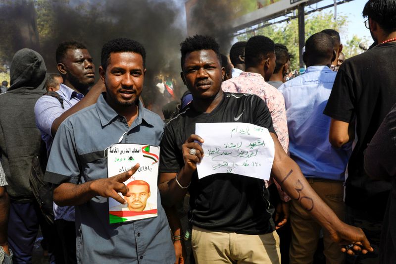 © Reuters. Sudanese civilians gather outside the court in Omdurman