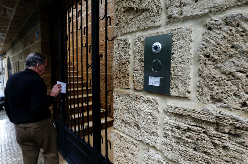 © Reuters. A man drops an envelope addressed to Carlos Ghosn through the entrance gate of what is believed to be Ghosn's house in Beirut