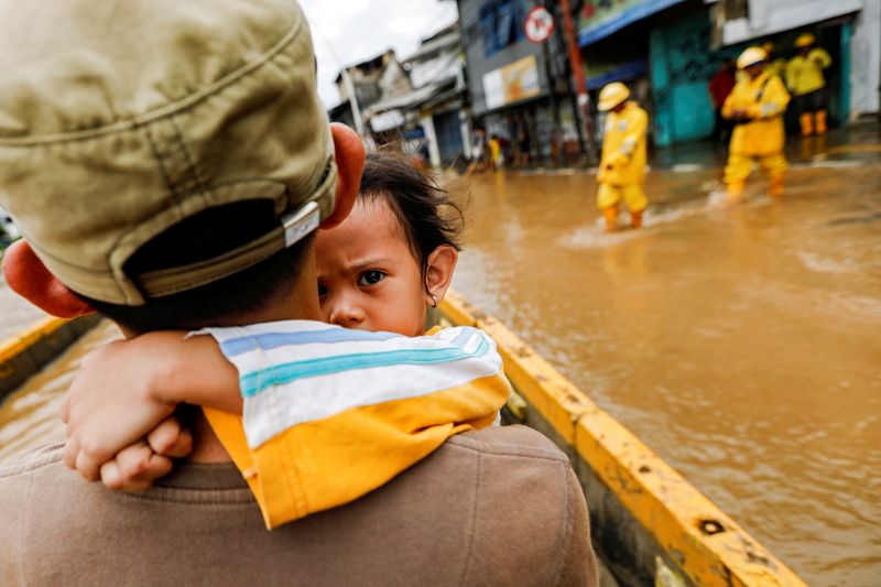 © Reuters. A girl is carried by her father across floodwaters in the Jatinegara area after heavy rains in Jakarta