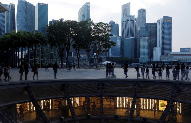 © Reuters. FILE PHOTO: People pass the skyline of the central business district along the Marina Bay Promenade in Singapore