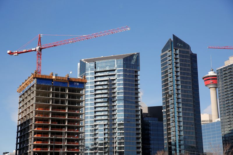 © Reuters. Workers guide construction equipment at a condominium development in Calgary