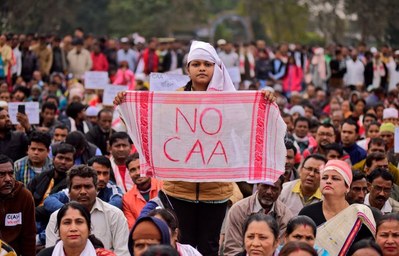 © Reuters. A demonstrator holds a piece of cloth locally known as "Gamosa" during a protest against a new citizenship law in Nagaon district