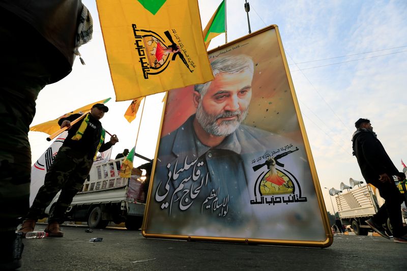 © Reuters. Kataib Hezbollah Iraqi militia hold the picture of the Iranian Major-General Qassem Soleimani, as they gather ahead of the funeral of the Iraqi militia commander Abu Mahdi al-Muhandis, in Baghdad