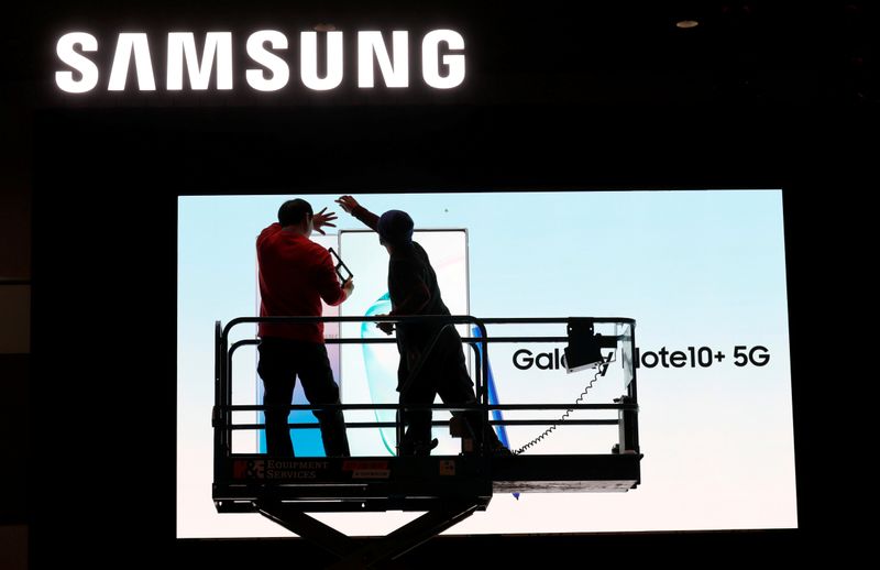 © Reuters. FILE PHOTO: Workers set up a Samsung display in the lobby of the Las Vegas Convention Center in preparation for the 2020 CES trade fair in Las Vegas