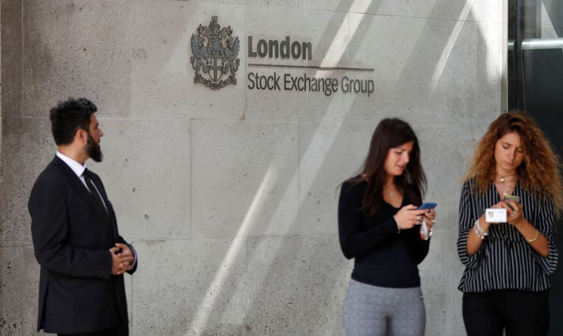 © Reuters. FILE PHOTO:  People check their mobile phones as they stand outside the entrance of the London Stock Exchange in London