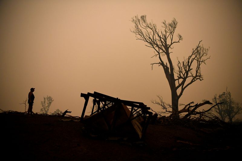 © Reuters. John Aish, residente de Cobargo, camina por una casa destruida en Cobargo, mientras continúan los incendios forestales en Nueva Gales del Sur