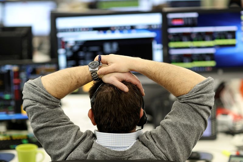 © Reuters. FILE PHOTO:  A broker looks at financial information on computer screens on the IG Index trading floor