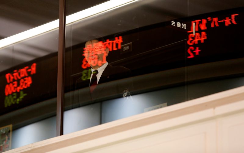 © Reuters. Stock prices are reflected on a window as an attendant waits for a ceremony marking the end of trading in 2019 at the Tokyo Stock Exchange in Tokyo